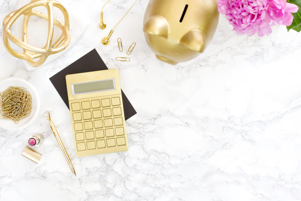 a pretty desk with gold calculator and piggy bank