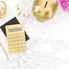 a pretty desk with gold calculator and piggy bank