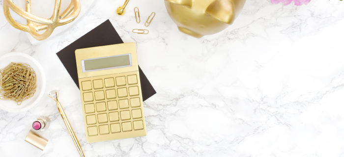 a pretty desk with gold calculator and piggy bank