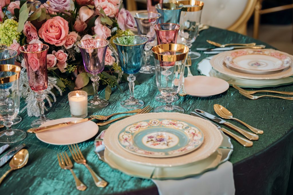 Iridescent luxurious wedding table setting.  multi coloured glassware and china, with lots of flowers.