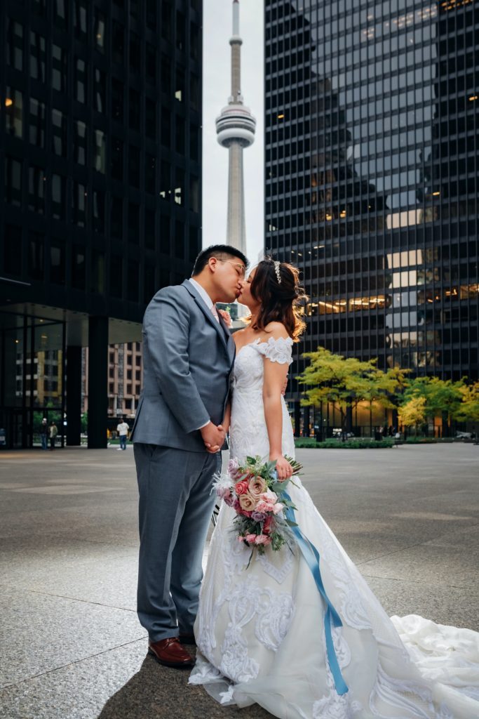 Chinese bride and groom kissing in front of CN Tower in downtown Toronto.