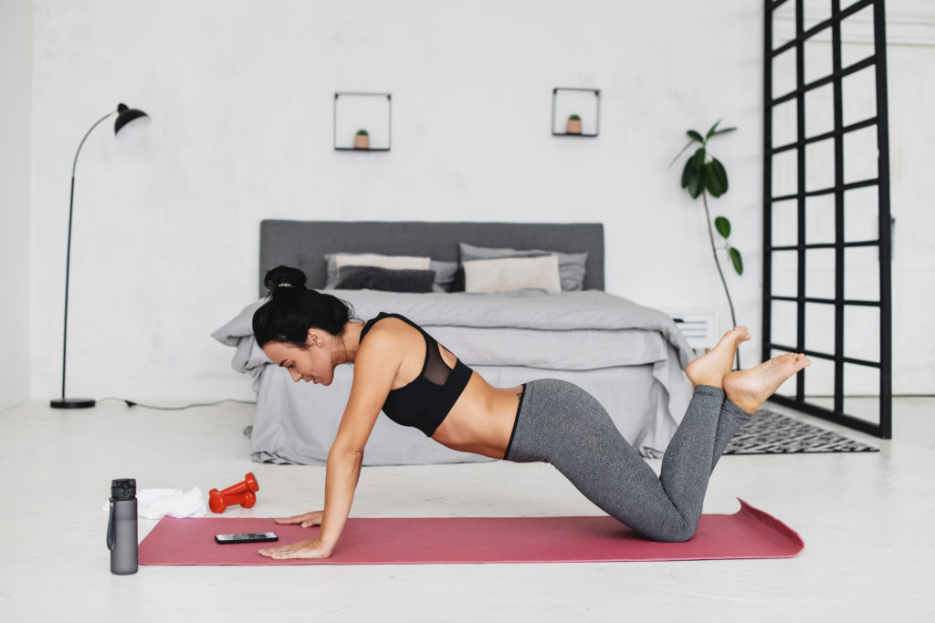 woman doing a plank in front of her bed