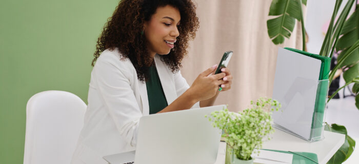wedding planner typing on phone in front of computer. social media management