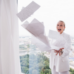 A business woman standing on a balcony with papers blowing away