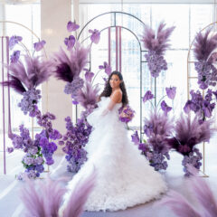 Beautiful black bride in front of an elaborate purple wedding ceremony backdrop.