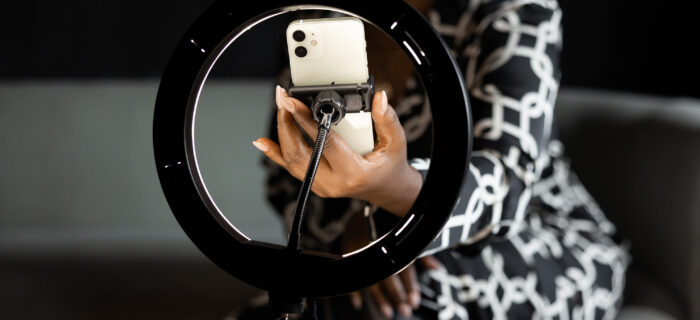 A well-dressed woman setting up a camera phone on a tripod. dramatic photo.